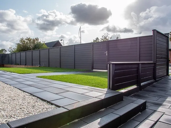 Dark WPC privacy fence installed around a garden